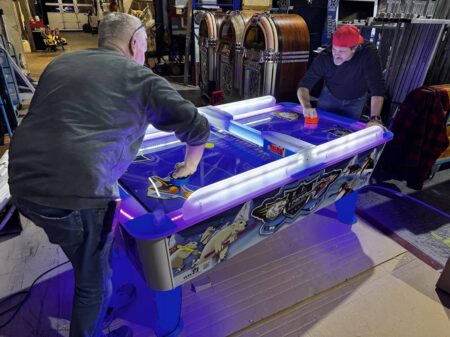 air hockey automat mit viel buntem led an dem 2 personen spielen.