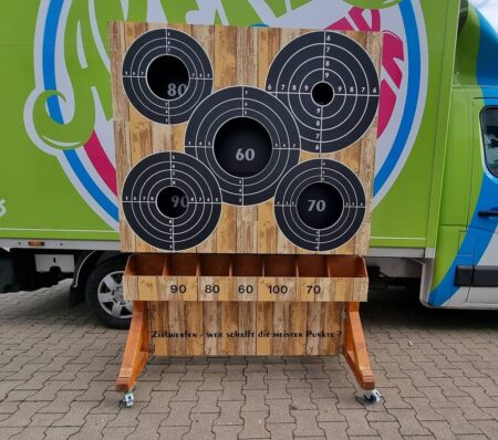 4 zielscheiben auf einem holzständer mit loch in das man bälle reinwerfen kann.