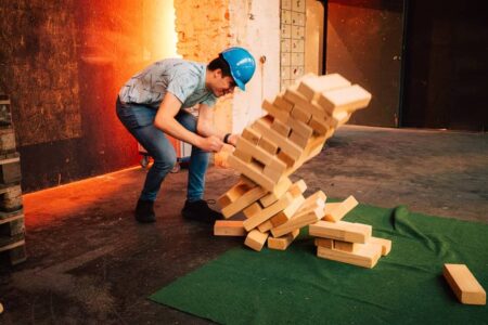 ein grosser holzklotz jenga tirm fällt um.
