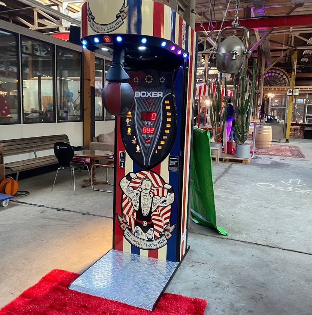 boxautomat auf rotem teppich. thema ist nostalgie. vorne ein gewichtheber aus den 70er jahren.design rot,blau, elfenbein.