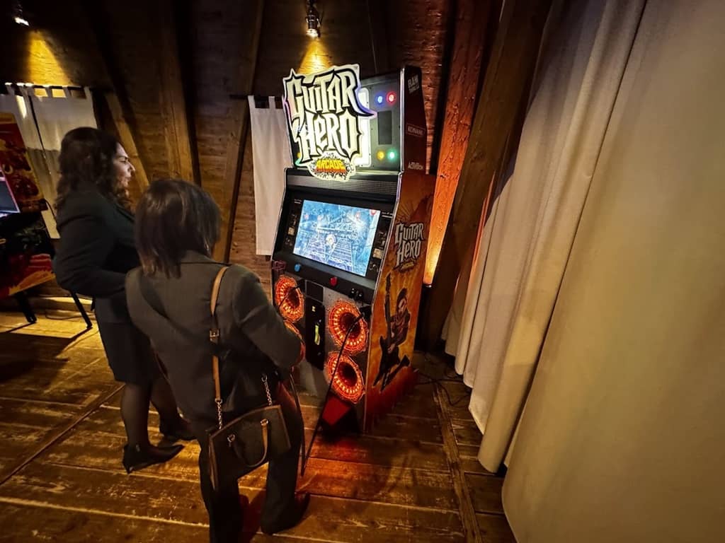 2 prsonen vor der arcade maschine guitar hero mit jeweils einer gitarre in der hand.