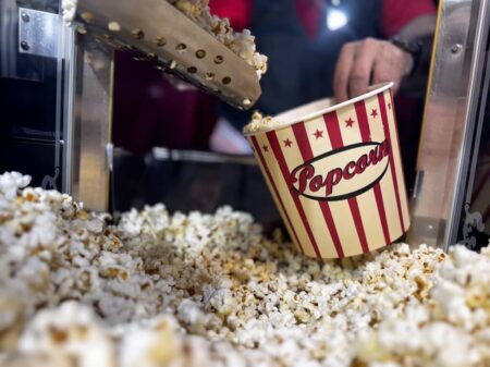 frisches popcorn wir per hand in einen pappbecher mit nostalgischer aufschrift abgefüllt.