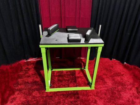 grüner armdrücktisch mit schwarzer platte auf rotem teppich.