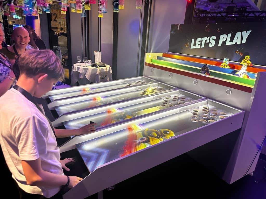 kinder spielen an dem kugelbahn automaten. der automat ist bunt beleuchtet.