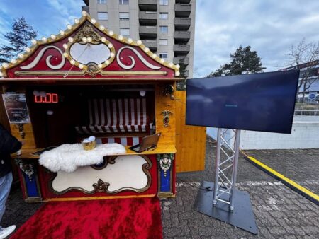 nostalgie marktbude mit rotem teppich. daneben ein grosser fernseher welcher das ranking anzeigt.