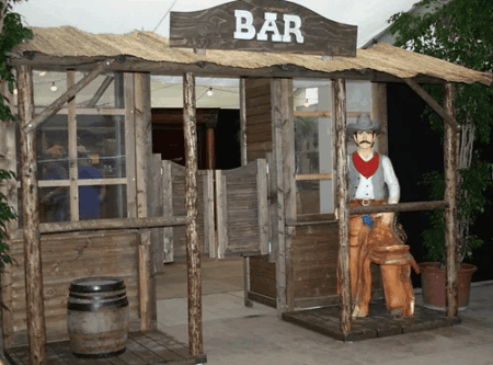 hölzerner western deko eingang mit einem cowboy davor.